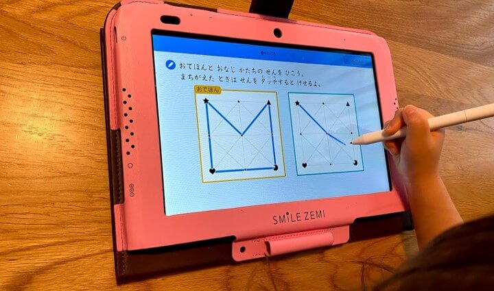 ピンク色のタブレットカバーのスマイルゼミで勉強する娘